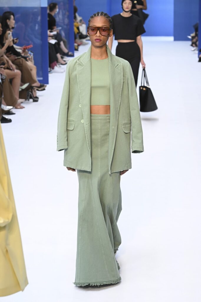 Моделът е облечен с пастелнозелен комплект с овърсайз сако и дълга пола