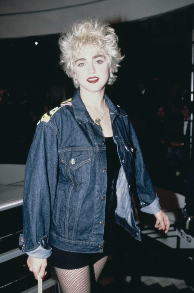 Мадона от 80-те облечена с дънково яке, мрежести чорапогащи и черна мини пола