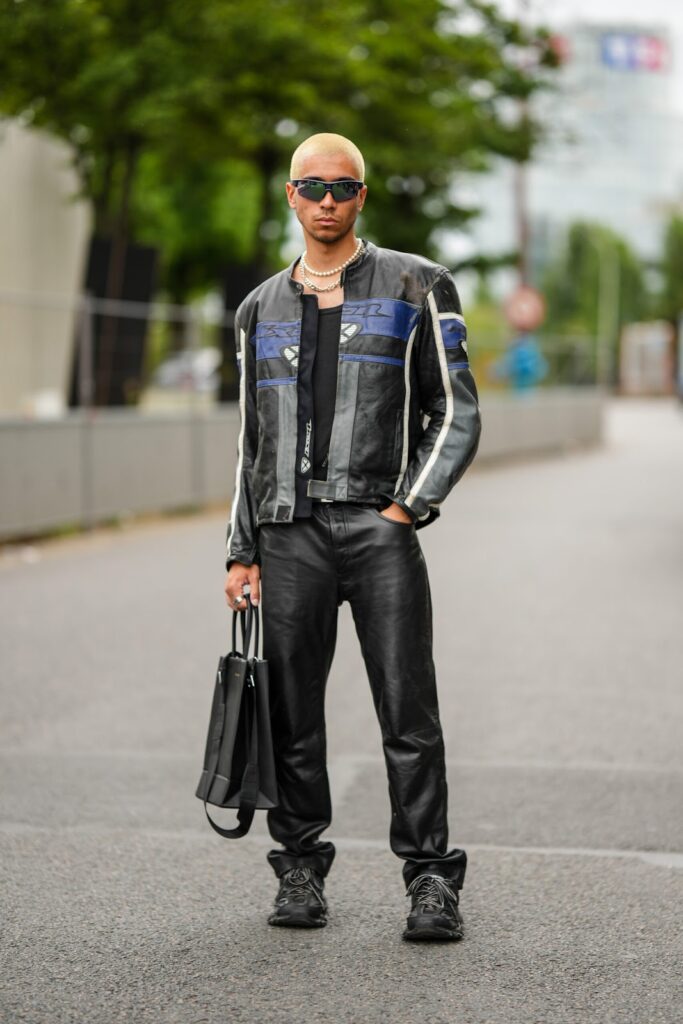 Мъж облечен със състезателно, черно кожено яке, черни кожени панталони и черни маратонки