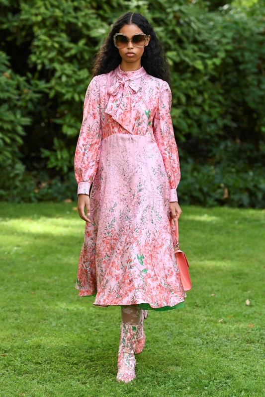 Моделът е облечен с флорална розова рокля с дълъг ръкав