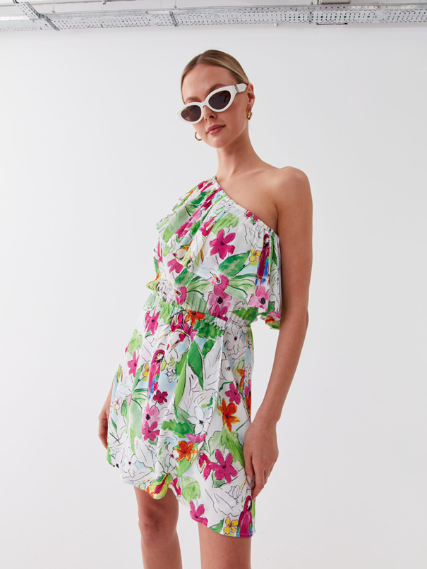 Жена с флорална мини рокля на едно рамо и слънчеви очила с бели рамки
