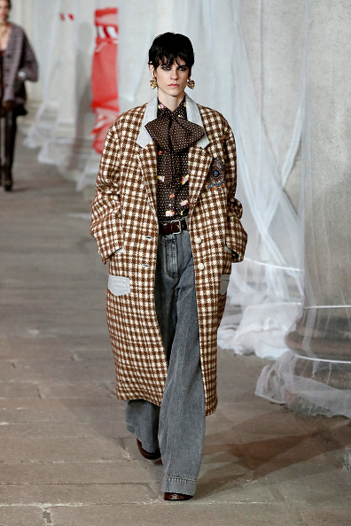Модел на моден падиум с дълго карирано дамско палто в кафяво и бежово