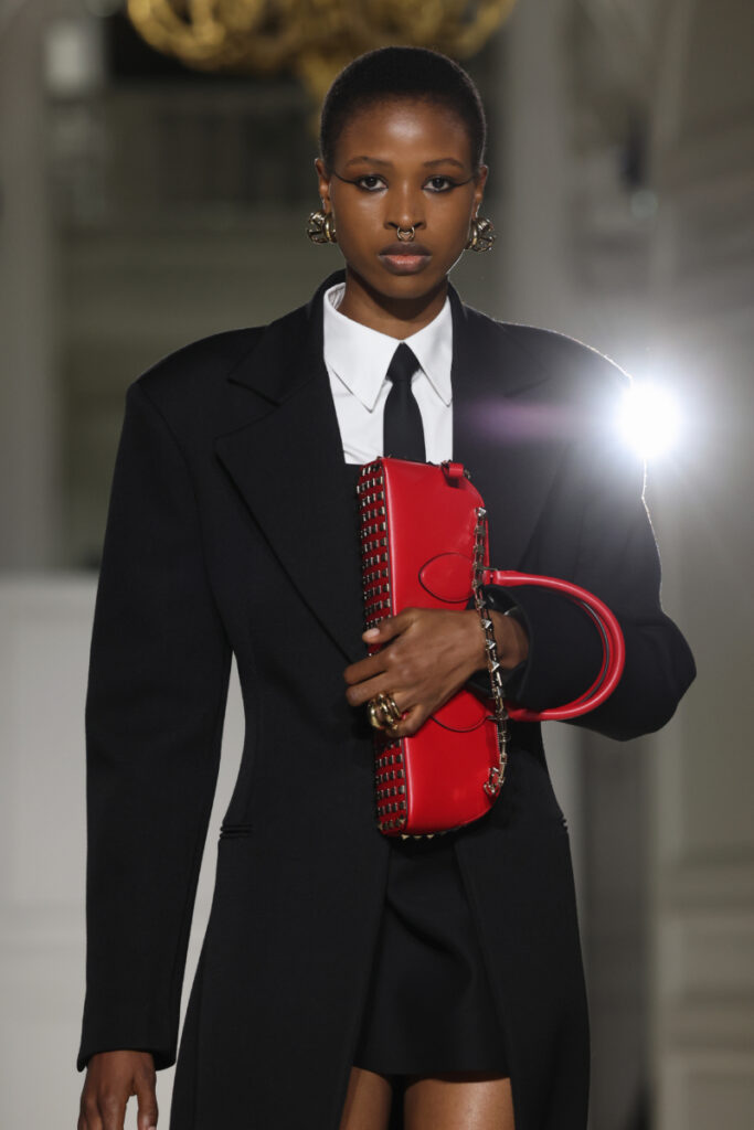 Моделът на модно модно ревю държи червена дамска чанта с капси