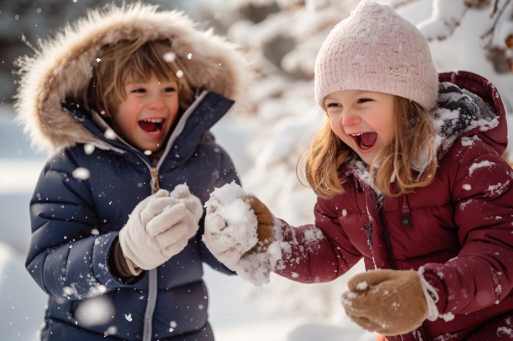 2 деца, момиченце и момченце играещи на снега облечени с пухени якета
