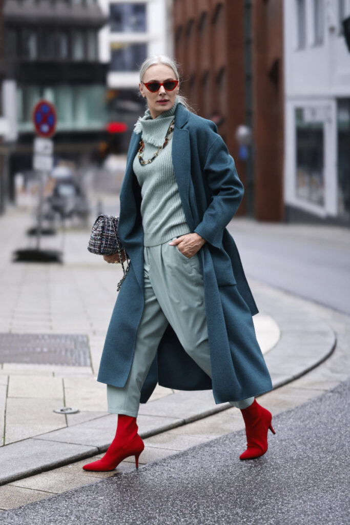жена облечена с палто в петролно синьо и червени боти на ток