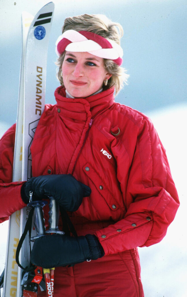Принцеса Даяна с червен гащеризон и двуцветна лента за глава в стил apres ski
