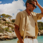 мъж на плажа облечен със светъл панталон и ленена риза с къс ръкав
